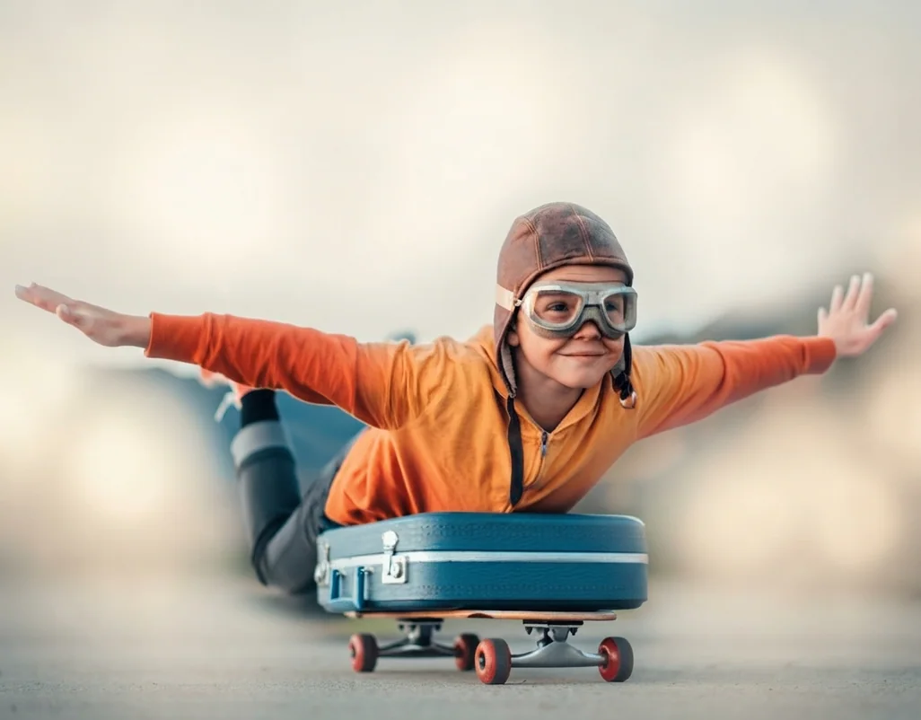 Niño jugando a volar sobre una maleta